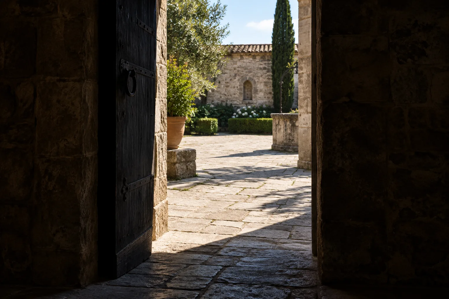 Depuis une entrée sombre, une cour lumineuse apparaît au fond du cadre.