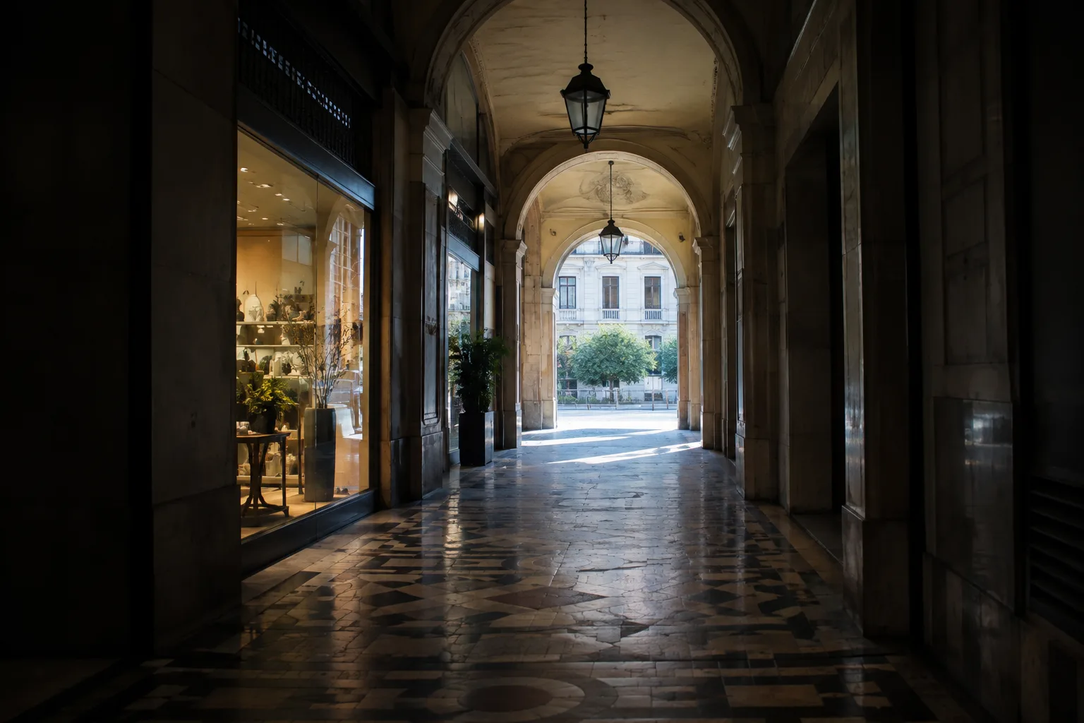 Depuis l’ombre d’une galerie, une vitrine et une ouverture lumineuse apparaissent au fond.