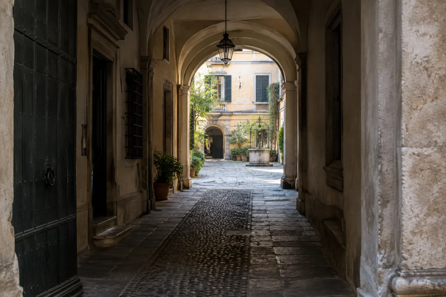 Un passage couvert relie une rue ombragée à une cour baignée de lumière.