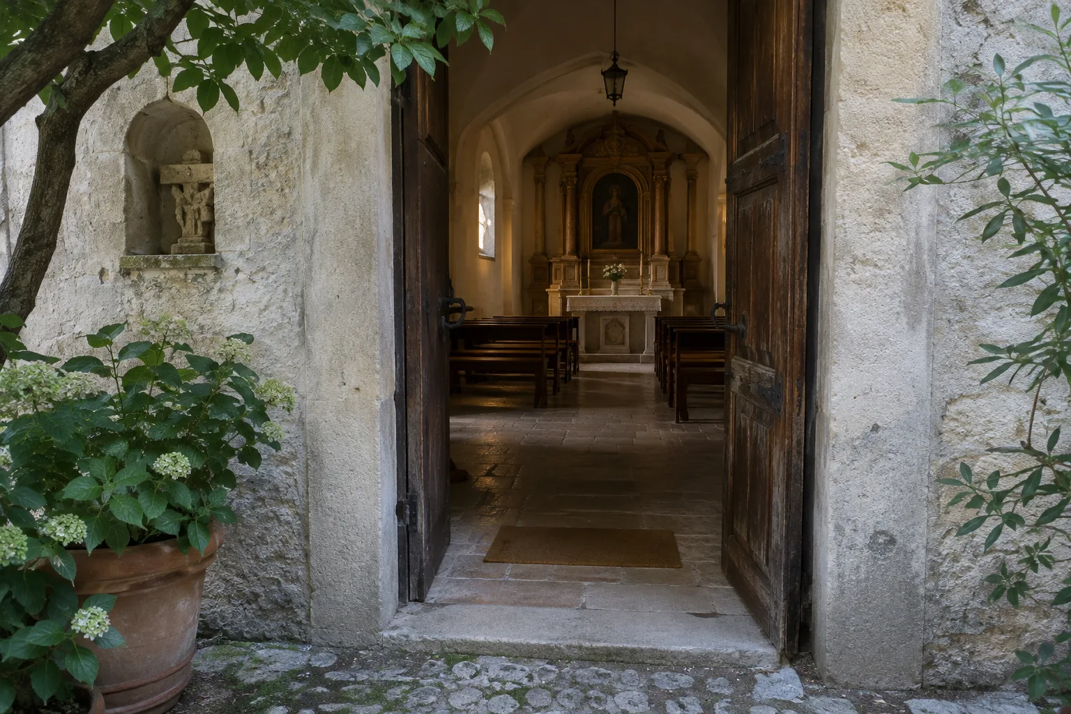 Une porte ouverte donne sur l’intérieur calme d’un lieu de culte depuis une cour ombragée.